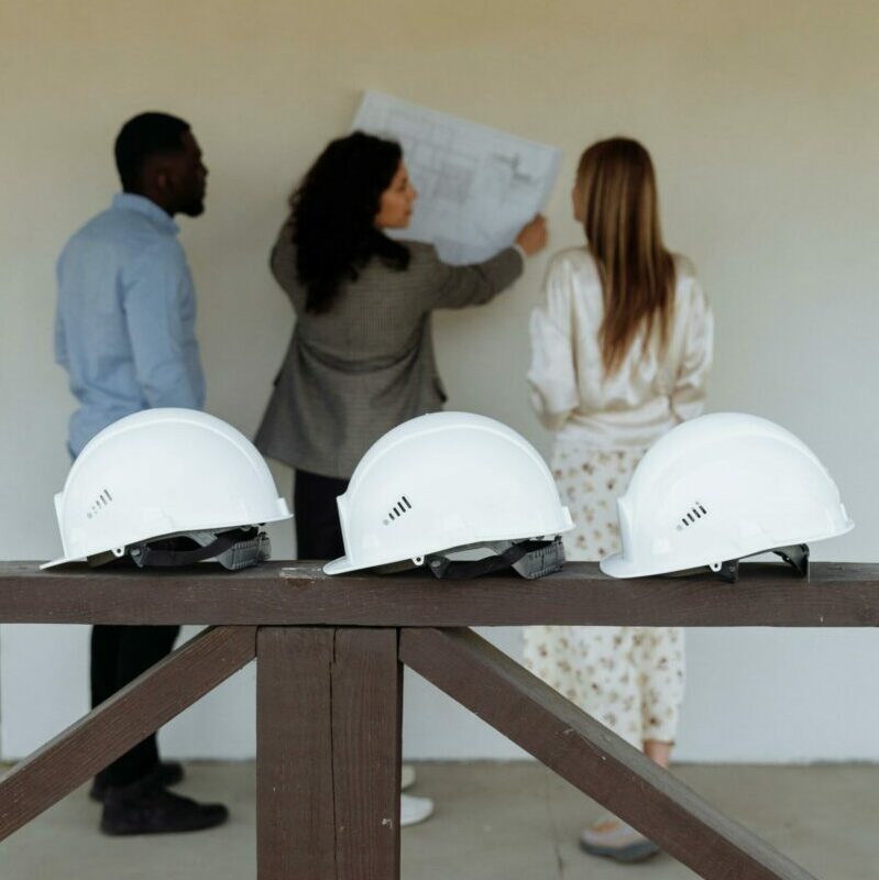 Group of architects discussing construction plans with hard hats in focus.